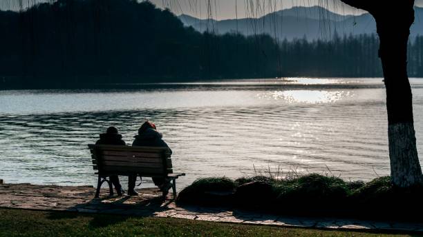 istock two people sitting on a bench overlooking the water at sunset 1554369773