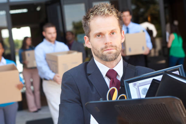 istock Man walking out of building with other laid off workers 155436989