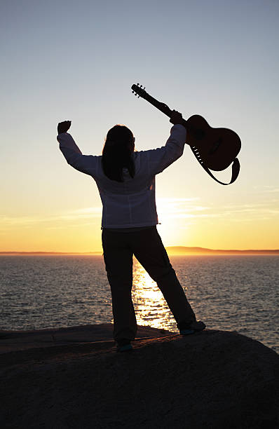 istock Woman Holding Guitar at Sunset 155437068