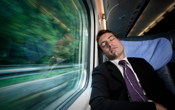 istock overworked  businessman sleeping and listening  music beside  window on train 155437110