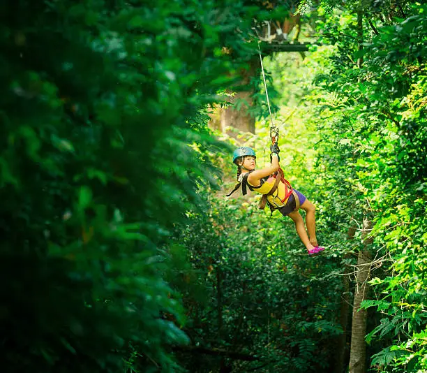 little girl doing a Canopy Tour Costa Rica, zip lines between trees.