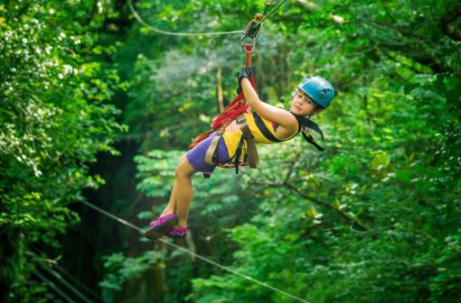 little girl doing a Canopy Tour Costa Rica, zip lines between trees.