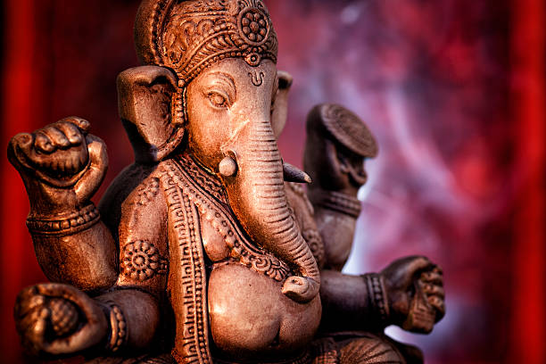 A statue of Ganesha, a deity of India on red background Deity of Ganesha from India on a red background. Some incense are making smoke in the back and it looks like a shrine in a temple. ganesha stock pictures, royalty-free photos & images