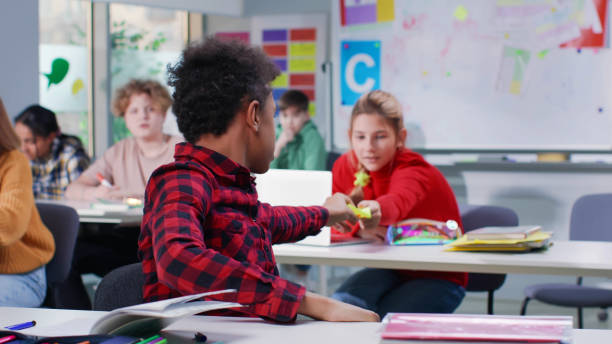 istock Teen girl pass note to classmate during exam in classroom 1554372380