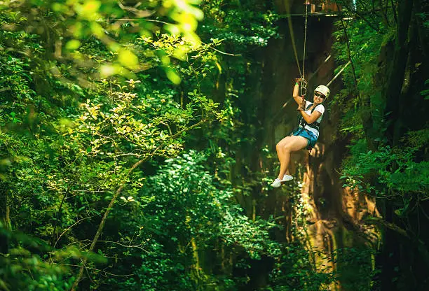 woman in her 40s doing a Canopy Tour Costa Rica, zip lines between trees.