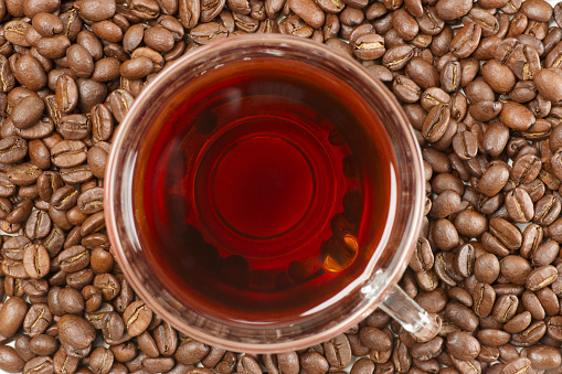 Medium-roasted coffee beans are smoky in a roasting pan. Copy space.