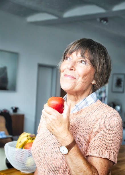 istock Senior woman looking up smiling while eating apple 155438097