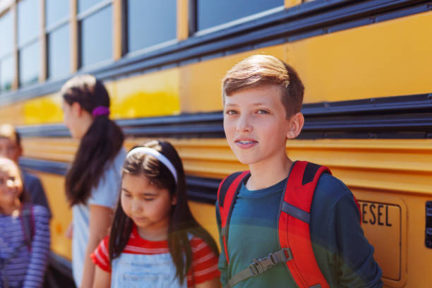 istock Kids waiting in queue to board school bus 1554382891