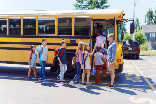 istock Elementary students boarding school bus outside school 1554383007