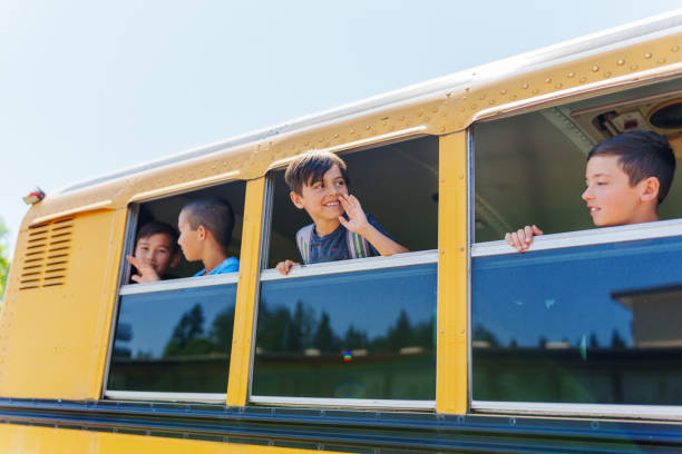 istock Happy elementary age boys waving out school bus windows 1554383426