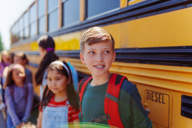 istock Happy elementary age boy waiting to board school bus 1554383430