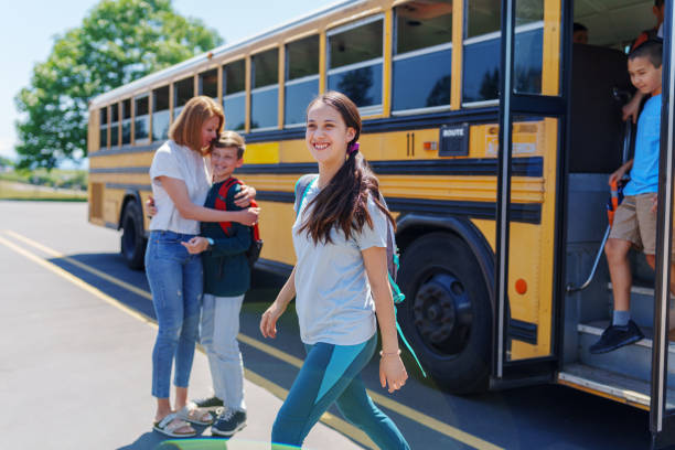 istock Smiling female student arriving at school bus stop after school 1554383439