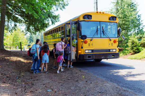 istock Students in queue boarding school bus in rural neighborhood 1554384002