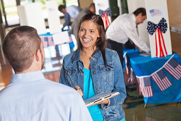 de voluntarios feliz haciendo la salida de la encuesta de la votación de las preguntas del centro electoral - voter registration fotografías e imágenes de stock