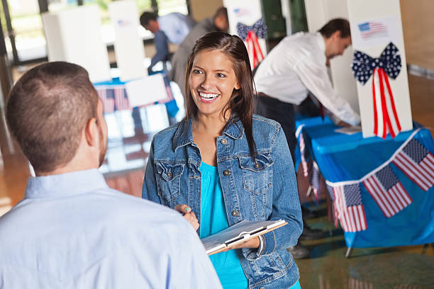 Happy volunteer asking exit poll questions at election voting center Happy volunteer asking exit poll questions at election voting center.  polling place photos stock pictures, royalty-free photos & images