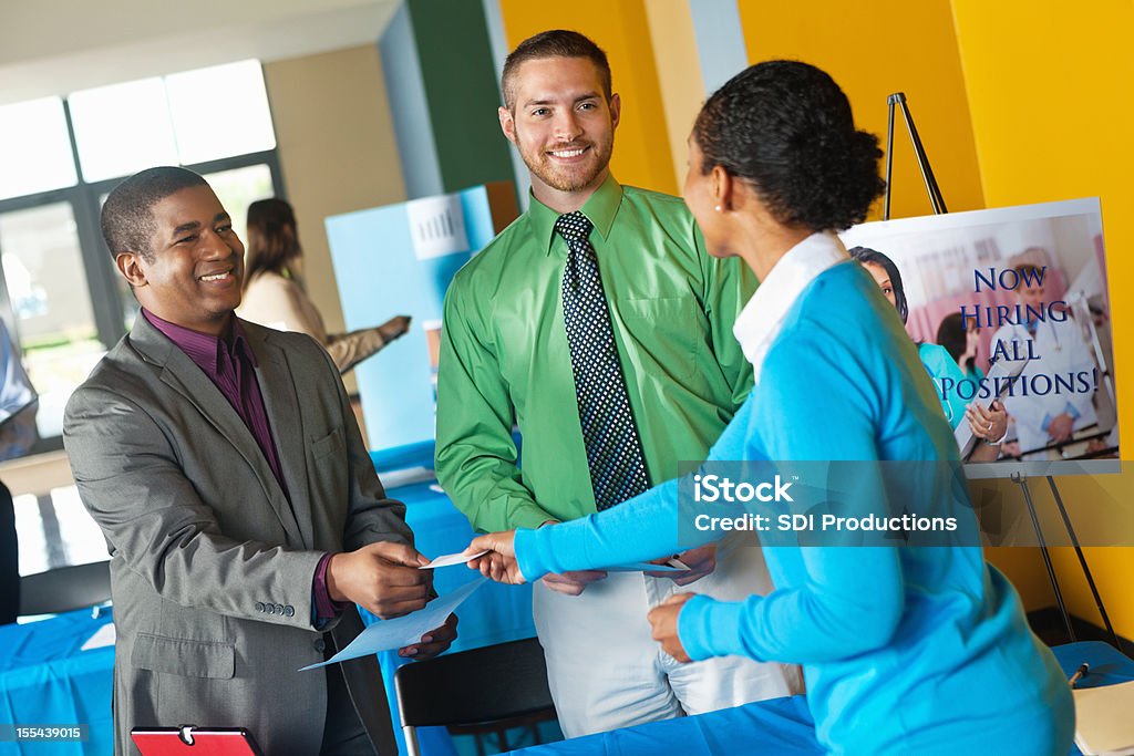 Young professional accepting business card from team at job fair Job Fair Stock Photo