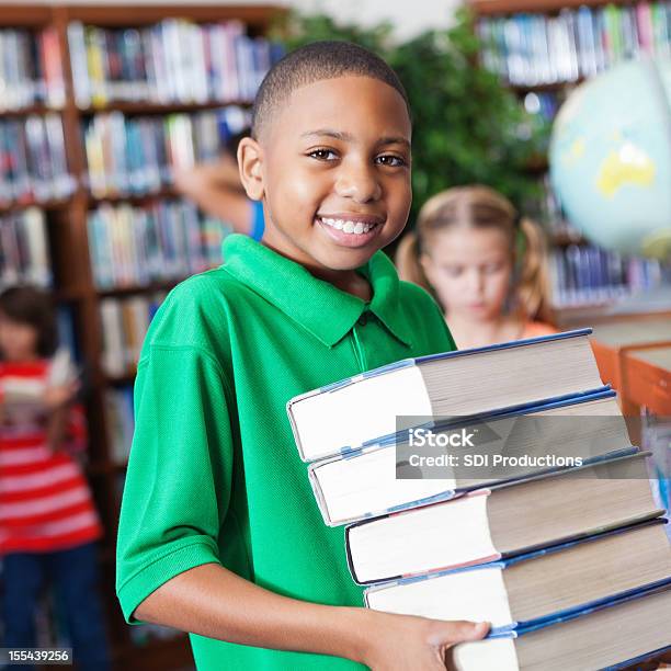 A Smart Student Checking Out Books In The School Library Stock Photo - Download Image Now