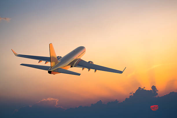 Passenger airplane flying above clouds during sunset stock photo