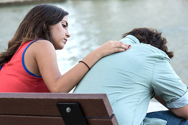Comforting friend Hispanic high school students, the teenage boy is crying with his hands in his face and the teenage girl is comforting him sad teenager boy crying outdoors in park stock pictures, royalty-free photos & images