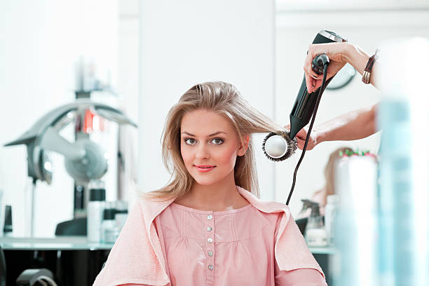 Young woman in a hair salon Young adult women getting her hair in a beauty salon, smiling at the camera. blow drying stock pictures, royalty-free photos & images