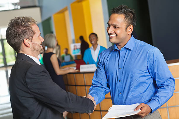 dos hombres de negocios estrechándose las manos intercambiando reanude en feria de trabajo - opportunity handshake job business fotografías e imágenes de stock