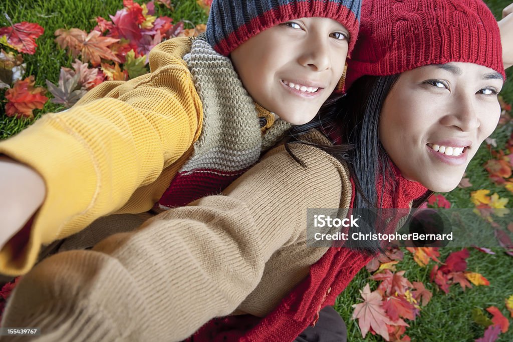 Mother and son sitting on autumn leaves Mother and son autumn portrait 25-29 Years Stock Photo