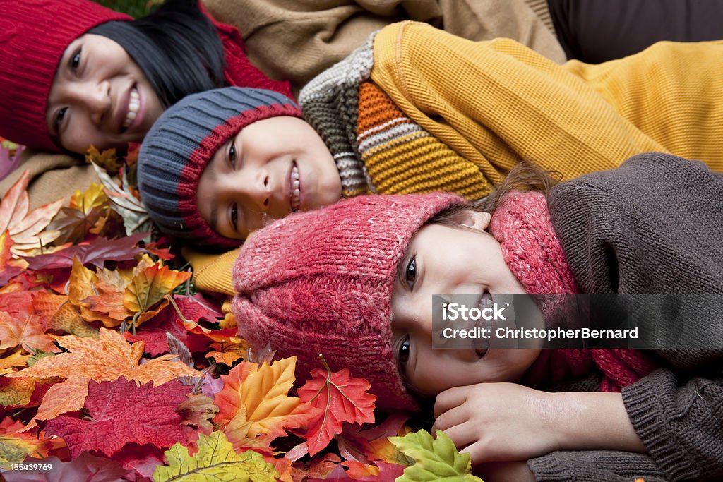 Asiatica famiglia Sdraiati su foglie d'autunno - Foto stock royalty-free di Autunno
