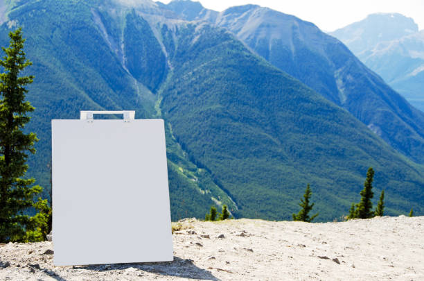 A blank billboard sign with copy space. The sign is in the Rocky Mountains and a scenic view is in the background.