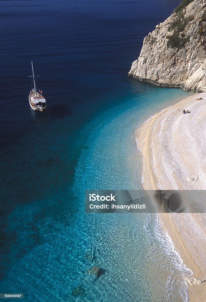 Sailboat and Beach Sailboat and sunbathing people in Kaputas Beach in Kalkan,Antalya,Turkey. Kaputas Stock Photo