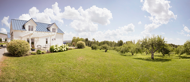 Eastern Townships Orchard with a small house and a beautiful partly cloudy Summer sky.