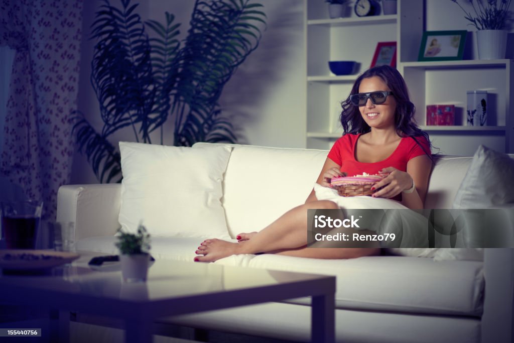 young woman watching television young woman in livingroom watching films with 3d glasses 20-24 Years Stock Photo