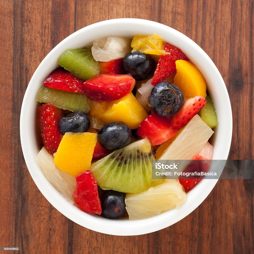 Fruit salad Top view of white bowl full of fruit salad containing strawberries, blueberries, orange, kiwi, pineapple and peach Fruit Stock Photo