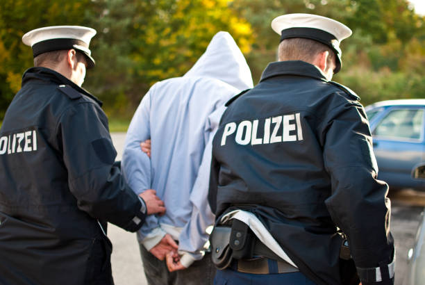 Two police officers are frogmarching a suspect Two police officers are frogmarching a criminal with a mask. law enforcement and crime stock pictures, royalty-free photos & images