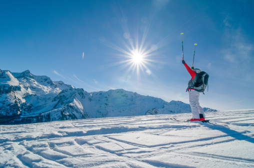 Skier Against Spectacular Mountainscape with sun raising arms up