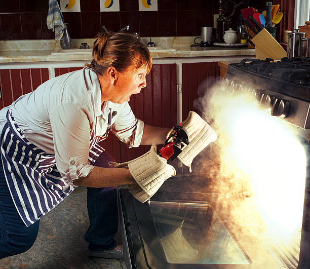 Woman and Oven Fire While Cooking in the Kitchen A woman is shocked and surprised as she discovers her dinner burning in the oven. Lots of smoke as she opens the oven door. kitchen on fire stock pictures, royalty-free photos & images