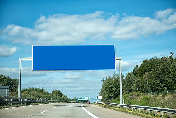 German highway under cloudscape View at a german highway, drivers view. The blank direction sign should be used as a copyspace. autobahn stock pictures, royalty-free photos & images