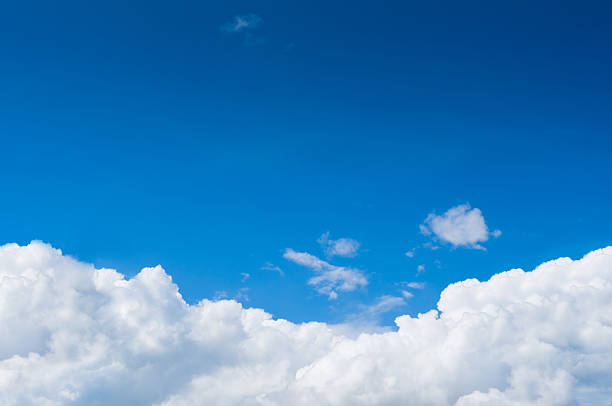 Blue sky with dramatic white clouds below stock photo