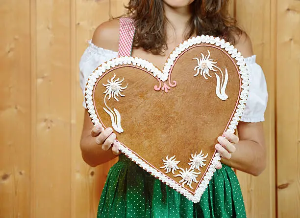 Beautiful woman in Dirndl Fashion holding a Lebkuchen Gingerbread Heart with copy space. Nikon D800e. Converted from RAW.