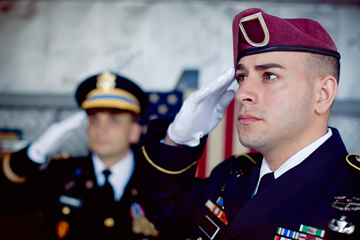 Two soldiers in uniform saluting.