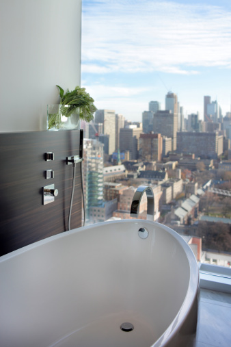 Luxury Bathroom view in modern North American city condo. Selective focus, with focus point on the tip of the faucet and bathtub edge.