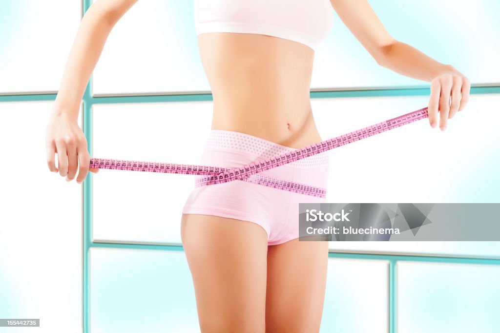 Young woman measuring her waistline. Abdomen Stock Photo