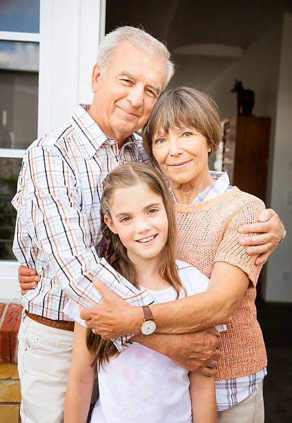Grandparents gently hold their baby in a green garden, showing tender care and deep connection across generations in a warm family moment.