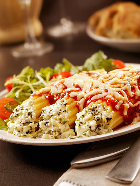 Stuffed Manicotti with Ricotta and Spinich Authentic Italian Stuffed Manicotti with Ricotta and Spinach topped with a Tomato sauce and Mozzarella Cheese with a side Salad and Garlic Bread -Photographed on Hasselblad H3D2-39mb Camera cooked selective focus vertical pasta stock pictures, royalty-free photos & images