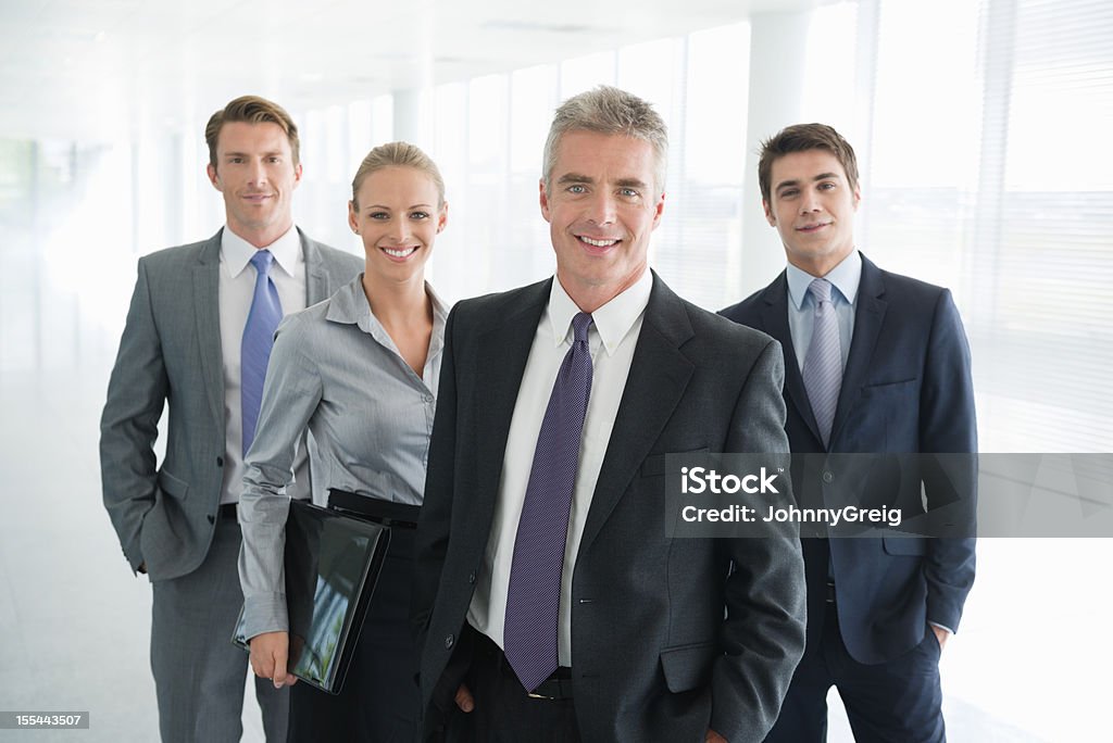 Write the title... Four people in business dress. Portrait of mature male business executive standing with colleagues 20-24 Years Stock Photo