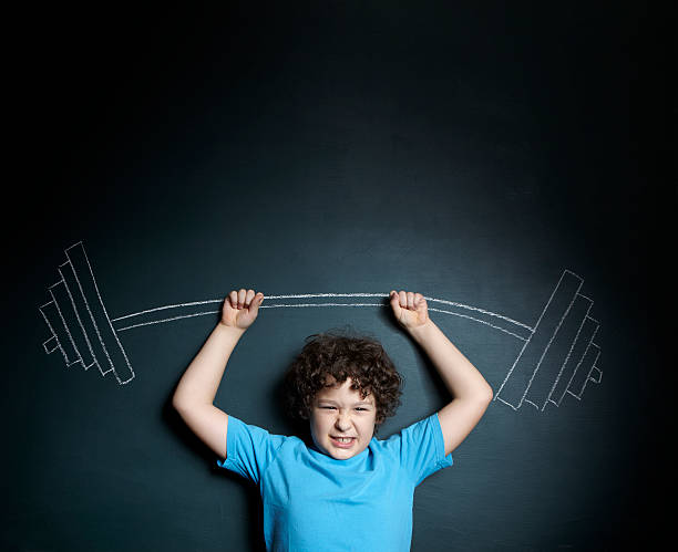 istock A little boy standing against a blackboard 155443693