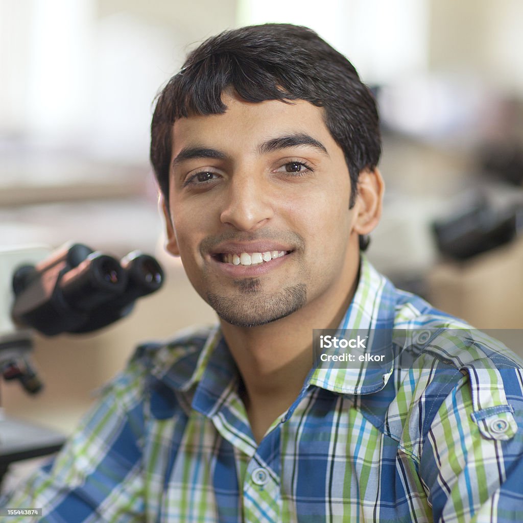 Felice studente indiano con microscopio In un laboratorio - Foto stock royalty-free di 20-24 anni