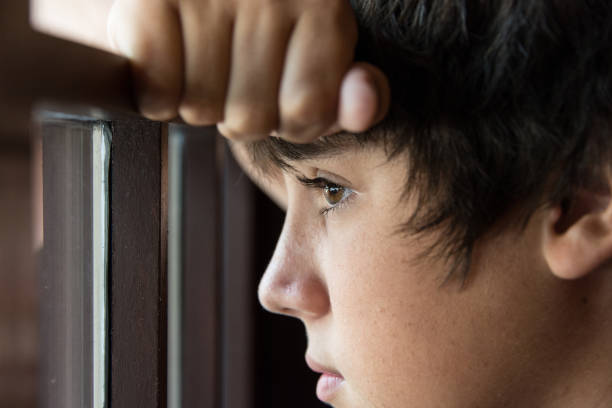 Pensive teenager looking through a window Pensive teenager looking through a window orphan stock pictures, royalty-free photos & images