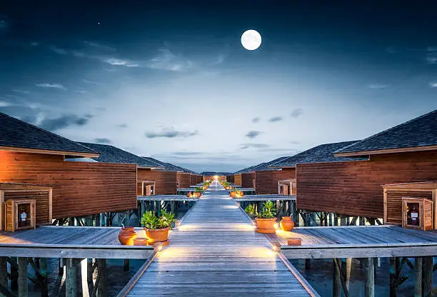 overwater bungalows boardwalk on maldives at full moon night 