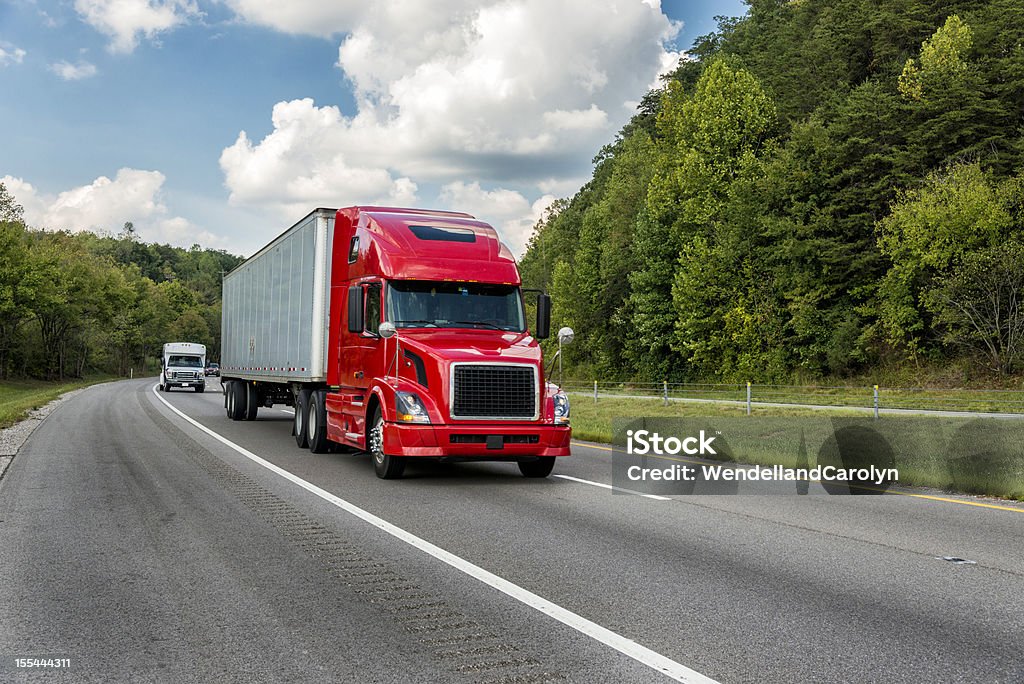 tractor rojo tráiler en un roadway a los árboles - Foto de stock de Camión articulado libre de derechos