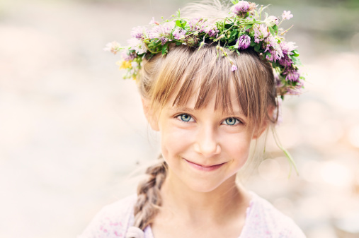 beautiful girl with a chaplet of flowers on her head that looks over her shoulder and smiles